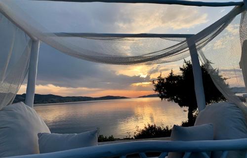 a view of a sunset from a bed with a view of the water at Eos Milos House in Pollonia