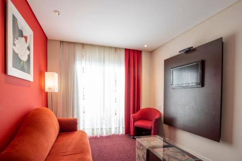 a living room with a couch and a television at Hotel Plaza Norte in Joinville