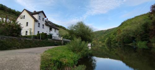 a house on a hill next to a river at Ferienwohnung Mila in Obernhof