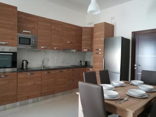 una cocina con armarios de madera y una mesa de madera con sillas. en The Premier Suite - Fully Airconditioned - Ample Parking, en Naxxar