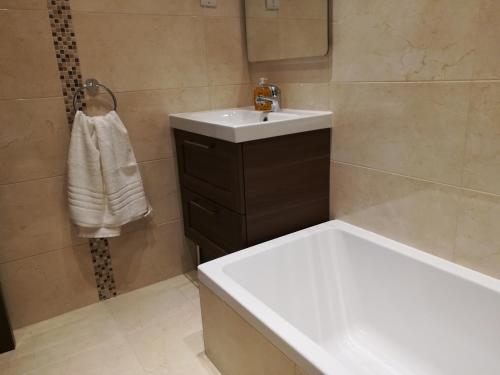 a bathroom with a white sink and a bath tub at The Premier Suite - Fully Airconditioned - Ample Parking in Naxxar