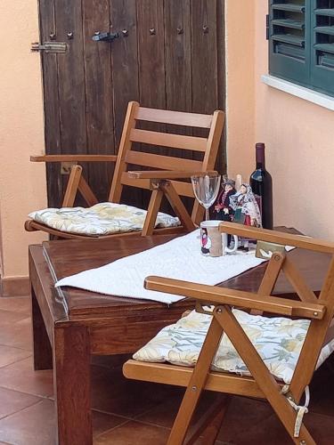 two wooden chairs and a table with wine glasses at Appartamento in zona residenziale in Orosei
