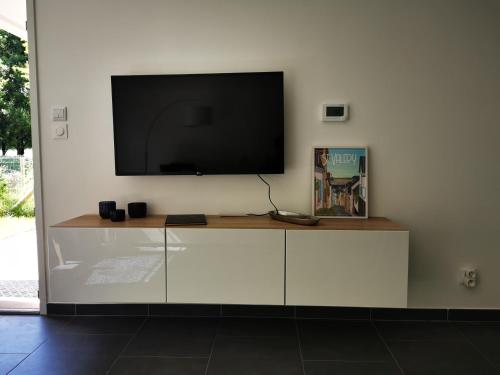 a living room with a tv on a white wall at Le Temps d'une Escale à St Wary in Saint-Valery-sur-Somme