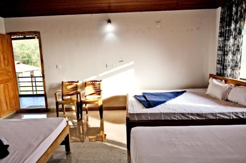a bedroom with two beds and a table and chairs at Sirimane Homestay - Swimming Pool, Food, Near to Falls & Trek in Sakleshpur