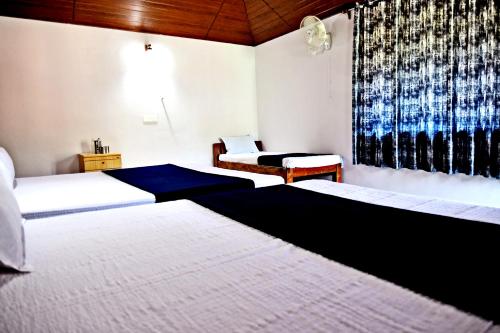 a hotel room with two beds and a window at Sirimane Homestay - Swimming Pool, Food, Near to Falls & Trek in Sakleshpur