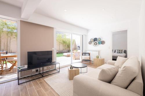 un salon avec un canapé et une télévision à écran plat dans l'établissement SERRENDY  COUP DE COEUR !  3p avec jacuzzi à pieds de la Croisette !, à Cannes