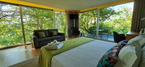 a bedroom with a bed and a couch and windows at Oak Nature in Vieira do Minho