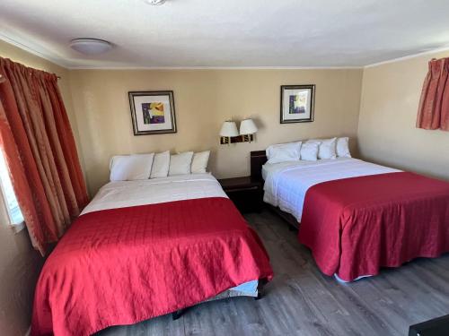 2 Betten in einem Hotelzimmer mit roter Bettwäsche in der Unterkunft Beachway Motel in Salisbury