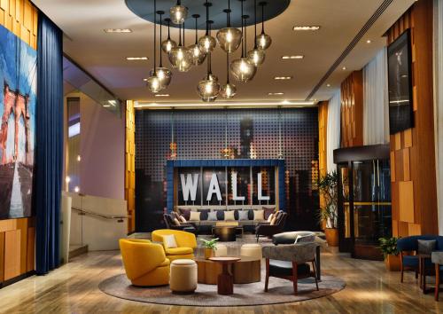 a lobby with a waiting area with yellow chairs and a wall at Hyatt Centric Wall Street New York in New York