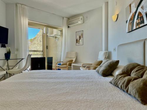 um quarto com uma grande cama branca, uma mesa e cadeiras em Chinasol Playa em Almuñécar