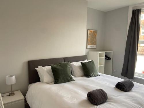 um quarto com uma grande cama branca com almofadas verdes em Central Southsea Boutique 2 Bedroom Flat em Portsmouth