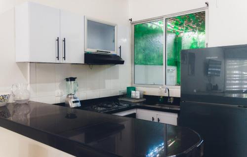 a kitchen with white cabinets and a black counter top at Casa de descanso con Jacuzzi privado - Girardot in Girardot