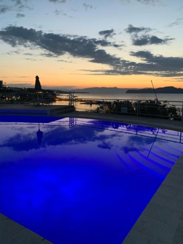 a pool with a view of the ocean at sunset at Terpsichori villa and apartments in Kalamaki