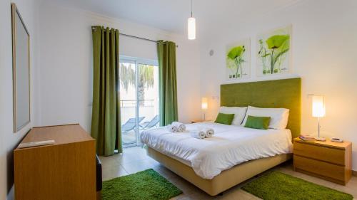 a bedroom with a large bed with green curtains at Quinta da Arbrotea in Lagos