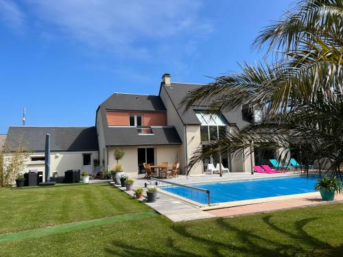 une maison avec une piscine dans une cour dans l'établissement Belle villa bord de mer avec piscine, à Urville-Nacqueville
