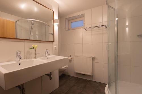 a white bathroom with a sink and a shower at Haus Almkreek in Kaprun