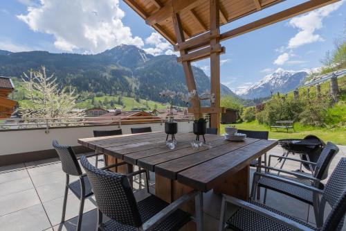 a wooden table and chairs on a balcony with mountains at Haus Almkreek in Kaprun