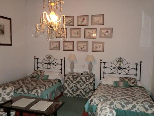 a bedroom with two beds and a chandelier at Palacio de la Rambla in Úbeda