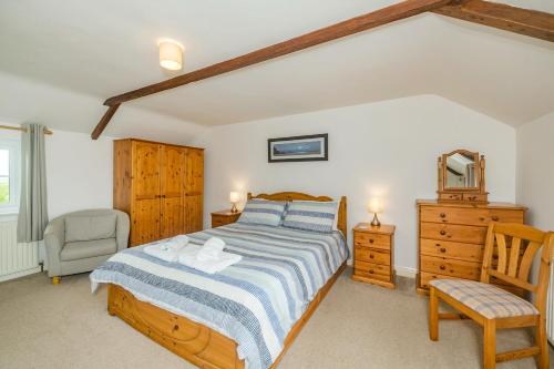 a bedroom with a bed and a chair and a dresser at Penbarden Barn in Bude