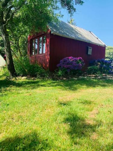 a red house with flowers in front of it at Gîte L'évidence in Saint-Caradec-Trégomel