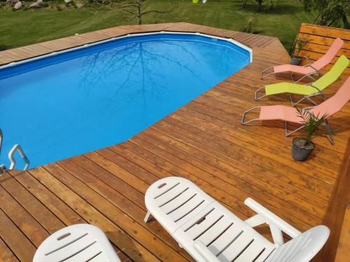 a deck with two chairs and a swimming pool at Gîte L'évidence in Saint-Caradec-Trégomel