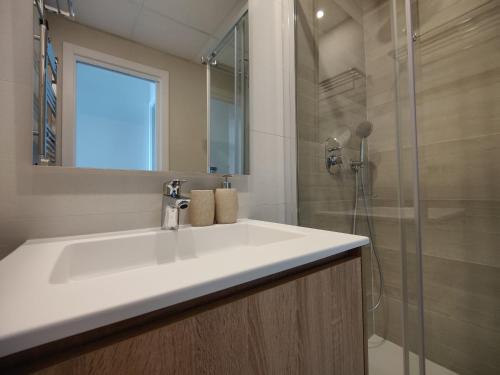 a bathroom with a white sink and a shower at SUNSET WAVES blue sky apartment in Benidorm