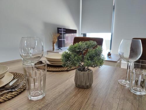 a table with glasses and a vase with a plant on it at SUNSET WAVES blue sky apartment in Benidorm