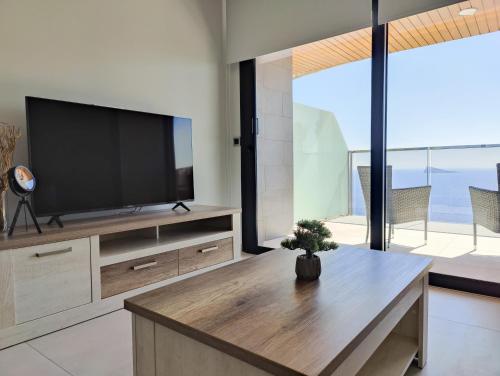 a living room with a flat screen tv and a table at SUNSET WAVES blue sky apartment in Benidorm