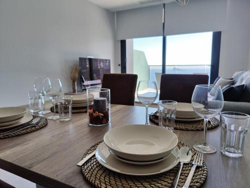 una mesa de madera con platos y copas de vino. en SUNSET WAVES blue sky apartment, en Benidorm