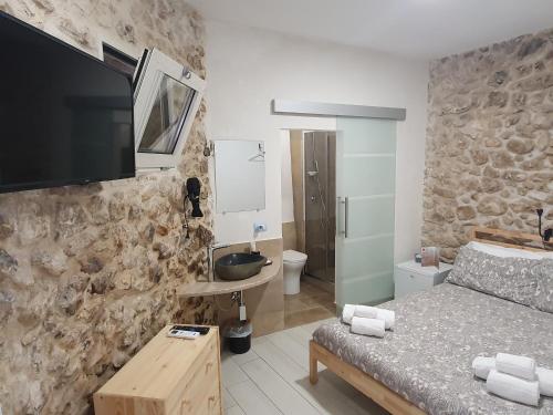 a bedroom with a bed and a tv on a stone wall at Il Daviduccio ibla in Ragusa