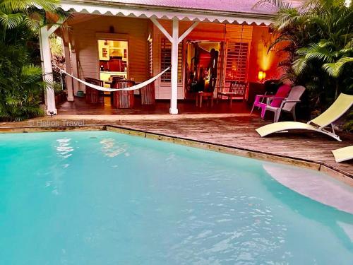 a swimming pool in front of a house at Villa Sisley, 2 chambres, piscine privée, plage à 100 m in Sainte-Rose