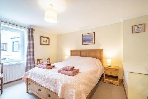 a bedroom with a bed with two towels on it at Creel Cottage in Eyemouth