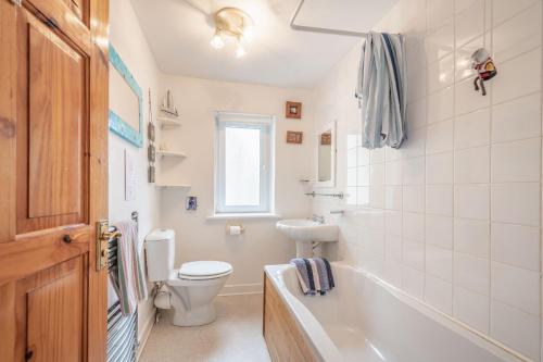 a bathroom with a tub and a toilet and a sink at Creel Cottage in Eyemouth