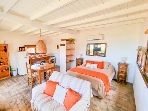 1 dormitorio con 2 camas, mesa y cocina en Cabañas Kundalini Punta del Diablo en Punta Del Diablo