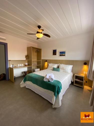 a bedroom with a large white bed with a ceiling at Pousada Relicário in Tiradentes