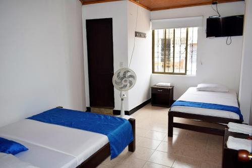 a bedroom with two beds and a fan at Hotel Descanso Inn Villavicencio in Villavicencio