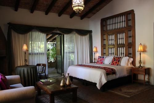 a bedroom with a large bed and a living room at Casa Magdalena Hotel Boutique in Morelia