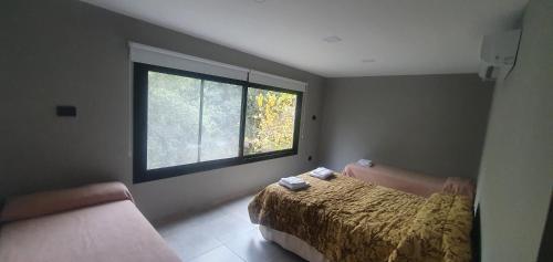 una camera da letto con un letto e una finestra di Cabaña con Pileta Sobre Camino Del Cuadrado En La Montaña Con Vistas Increíbles - Cerca De Todo a Río Ceballos