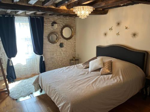 a bedroom with a large bed with a chandelier at Havre d'amour in Mondeville