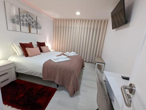 a bedroom with a large bed and a television at Silvaapartments in Praia da Barra