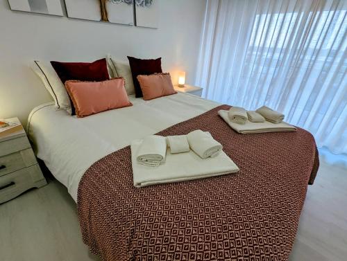 a large bed with two towels on top of it at Silvaapartments in Praia da Barra