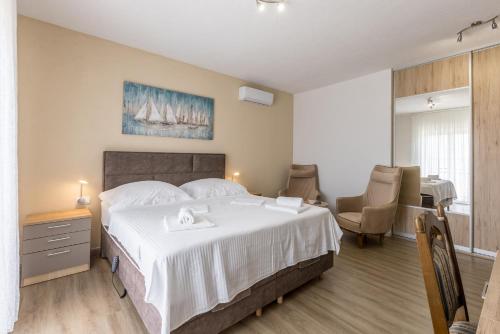 a bedroom with a large white bed and a table and chairs at Bed & Breakfast Senator in Podstrana