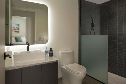 bagno con servizi igienici, lavandino e specchio di YOTELPAD Miami a Miami