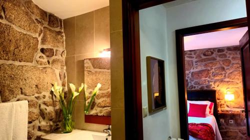 a bathroom with a stone wall and a vase of flowers at Casa do Charco Peneda Gerês in Parada