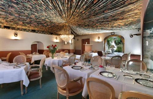 Un restaurante con mesas y sillas blancas y una lámpara de araña. en Contact Hôtel de France Contres-Beauval-Cheverny, en Contres