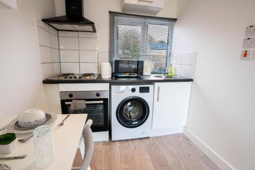 a kitchen with a washing machine and a table at No 02 Studio Flat Available near Aylesbury Town Station in Buckinghamshire