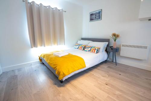 um quarto com uma cama com um cobertor amarelo em No 02 Studio Flat Available near Aylesbury Town Station em Buckinghamshire