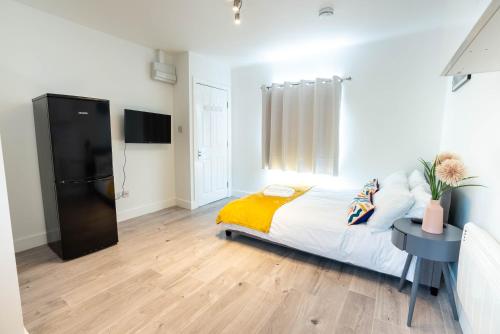 a bedroom with a bed and a table and a tv at No 02 Studio Flat Available near Aylesbury Town Station in Buckinghamshire