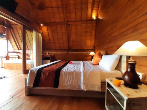 a bedroom with a bed and a table with a lamp at Pondok Gandalangu Ubud-Dikelilingi Hamparan Sawah in Ubud