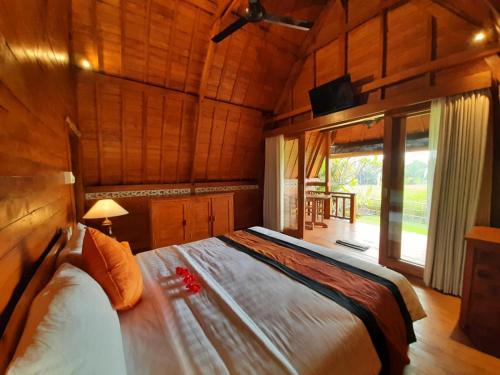 1 dormitorio con 1 cama grande en una habitación de madera en Pondok Gandalangu Ubud-Dikelilingi Hamparan Sawah, en Ubud